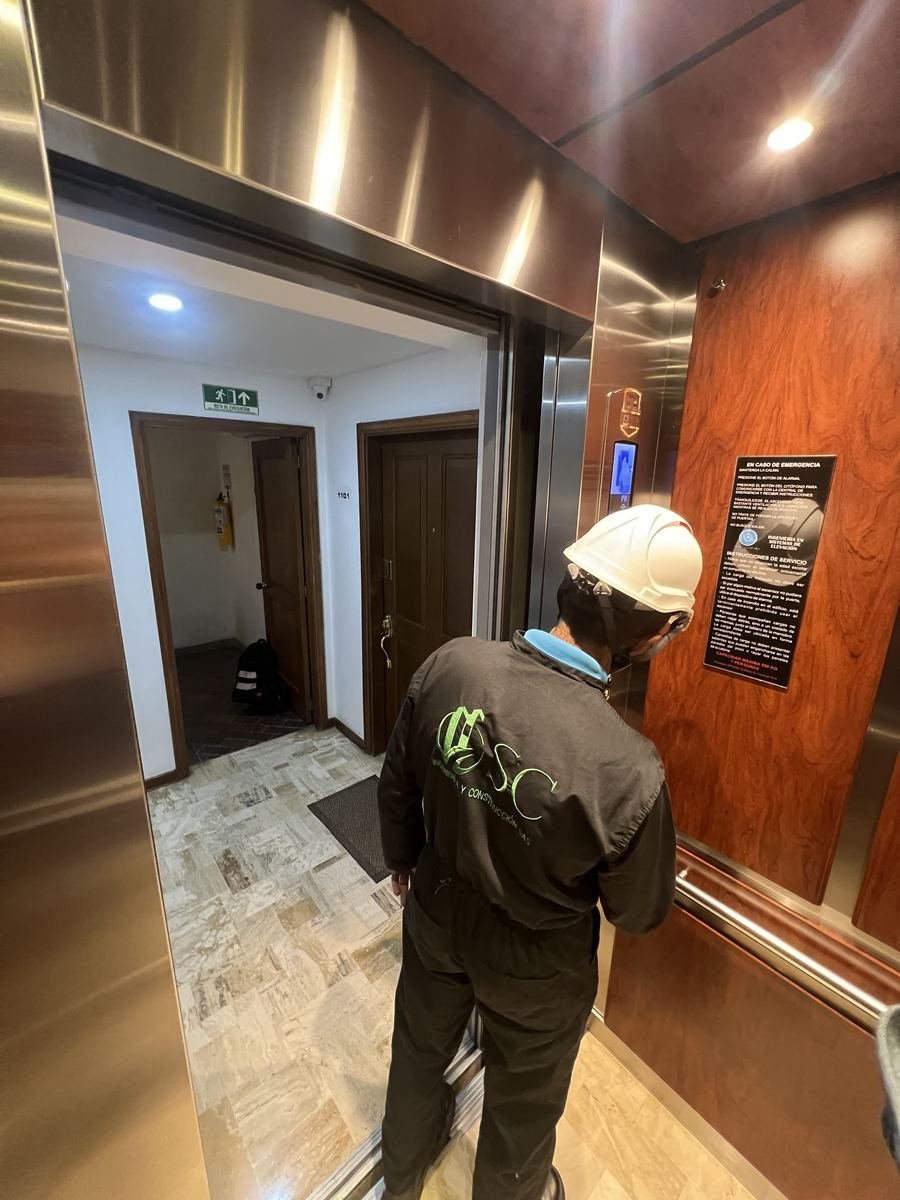 Técnico de SC Ingeniería, con casco y uniforme, atendiendo el ascensor de un edificio en Bogotá